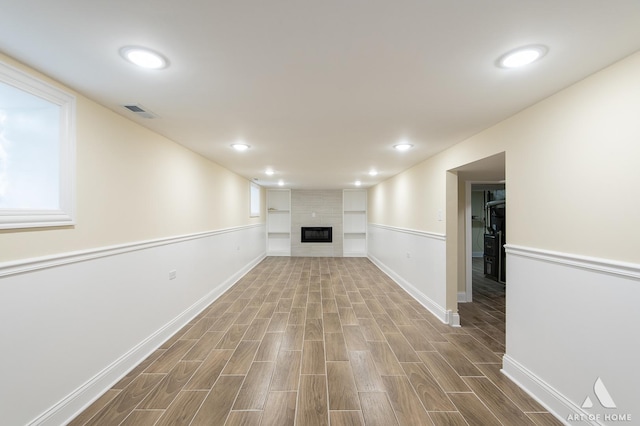 below grade area featuring visible vents, baseboards, a tile fireplace, wood tiled floor, and recessed lighting