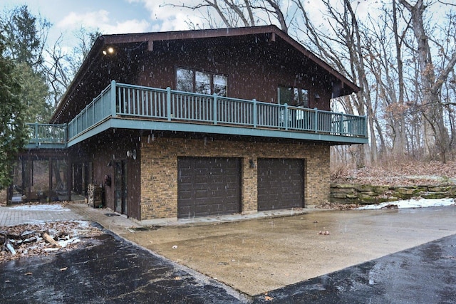 rear view of property featuring brick siding, driveway, and a garage