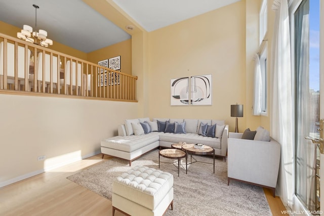 living area with baseboards, an inviting chandelier, and wood finished floors