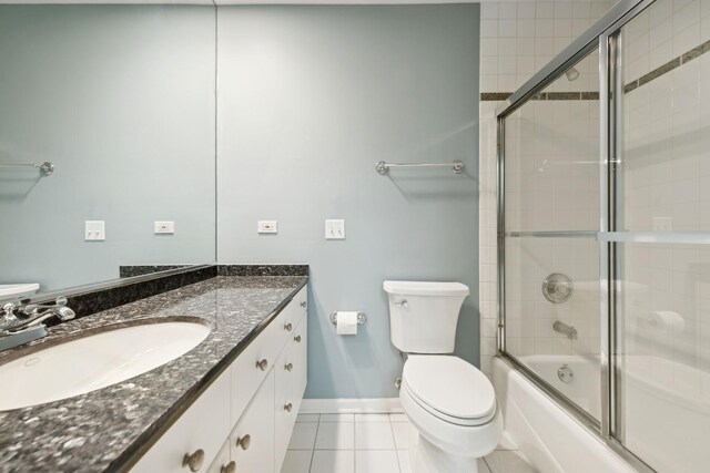 full bathroom featuring bath / shower combo with glass door, toilet, vanity, baseboards, and tile patterned floors