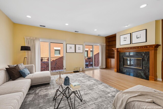 living area featuring recessed lighting, a fireplace, baseboards, and wood finished floors