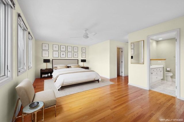 bedroom featuring light wood-type flooring, ensuite bath, baseboards, and ceiling fan