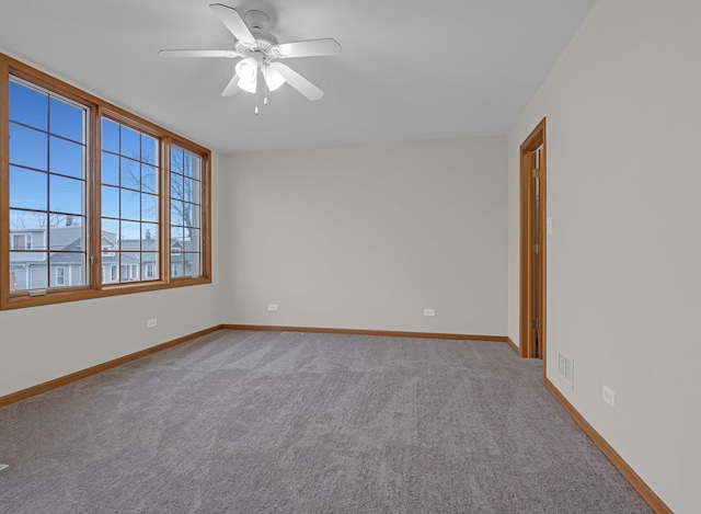 carpeted empty room with visible vents, a ceiling fan, and baseboards