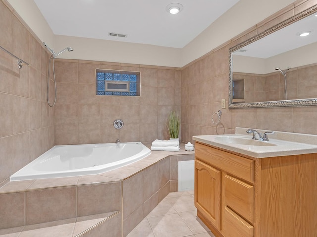 full bathroom featuring tile walls, visible vents, tiled shower / bath combo, vanity, and tile patterned flooring