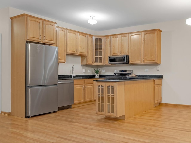 kitchen with glass insert cabinets, light wood-style flooring, light brown cabinets, and appliances with stainless steel finishes