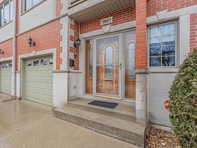 view of exterior entry with a garage and brick siding