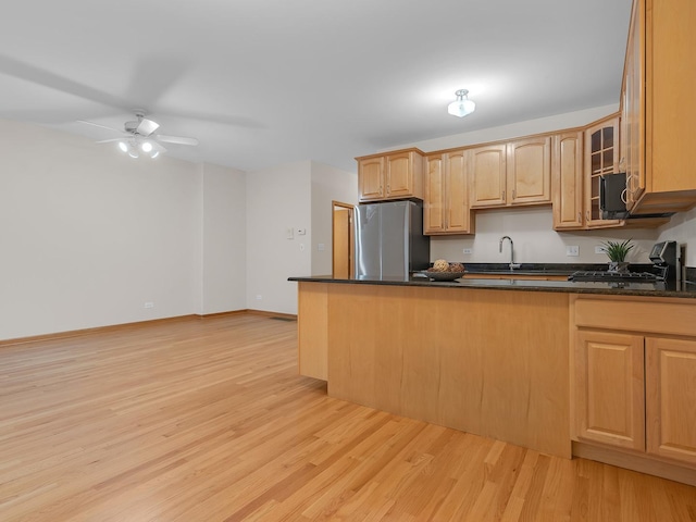 kitchen with light wood finished floors, stove, glass insert cabinets, freestanding refrigerator, and a peninsula