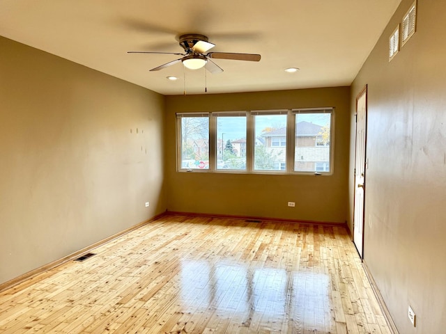 spare room with ceiling fan, baseboards, visible vents, and light wood-style floors