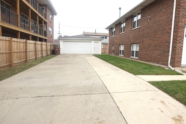 exterior space with an outbuilding, brick siding, a detached garage, and fence