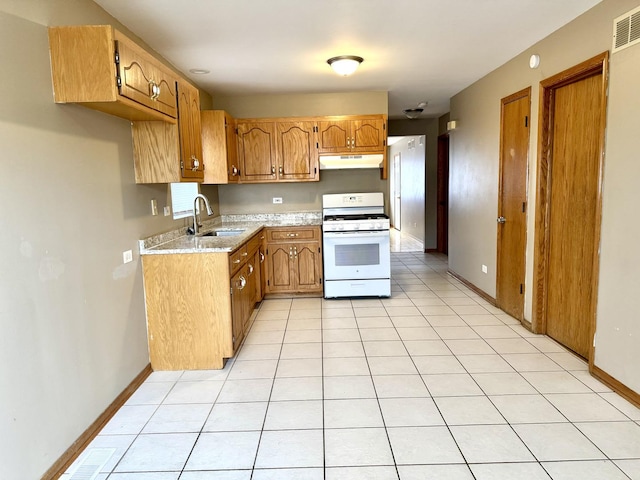 kitchen with under cabinet range hood, white range with gas cooktop, light tile patterned floors, and a sink