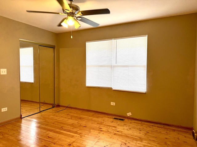 unfurnished bedroom featuring baseboards, visible vents, wood-type flooring, ceiling fan, and a closet