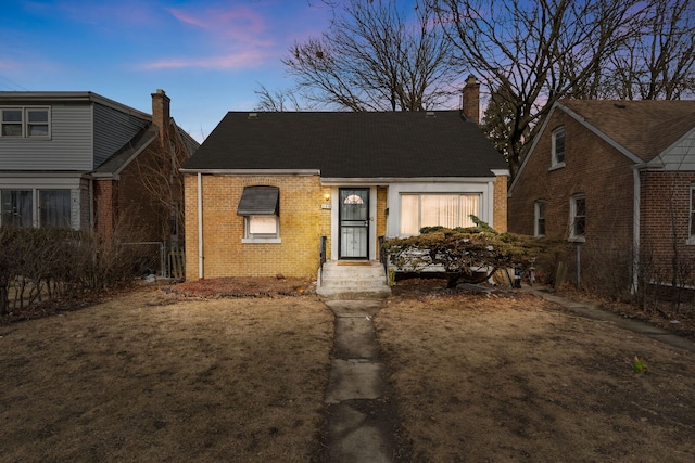 view of front of property featuring brick siding and a chimney