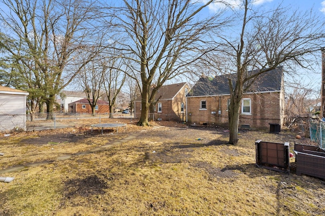 view of yard featuring a trampoline and fence