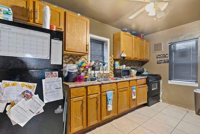 kitchen featuring light tile patterned floors, a sink, visible vents, decorative backsplash, and black appliances