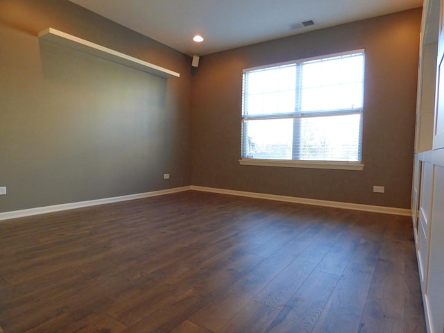 empty room featuring dark wood-type flooring, recessed lighting, visible vents, and baseboards