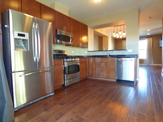 kitchen with dark countertops, appliances with stainless steel finishes, decorative backsplash, and dark wood-style flooring