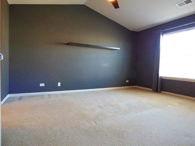 carpeted spare room featuring ceiling fan, baseboards, visible vents, and vaulted ceiling