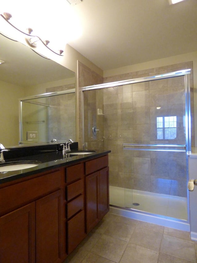 bathroom featuring a stall shower, tile patterned flooring, a sink, and double vanity