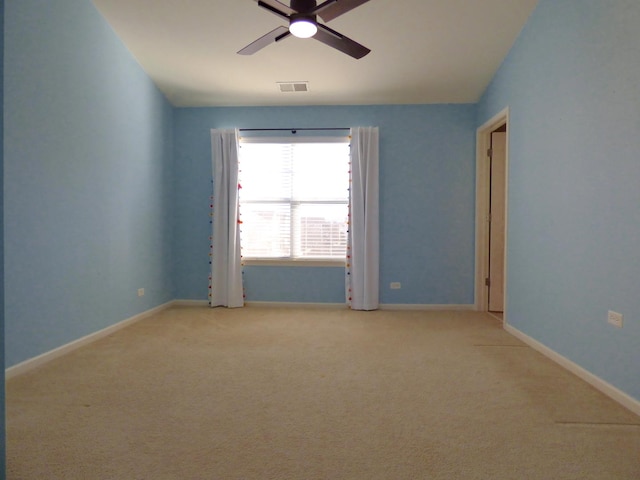 unfurnished room with ceiling fan, light colored carpet, visible vents, and baseboards