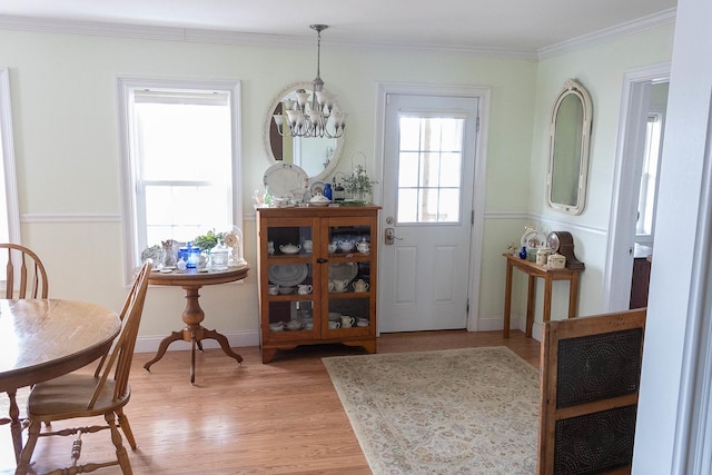 dining room featuring light wood-style floors, a healthy amount of sunlight, a notable chandelier, and ornamental molding