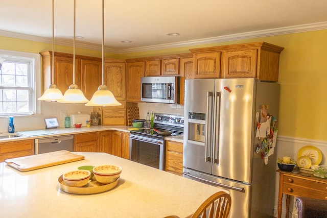 kitchen with ornamental molding, appliances with stainless steel finishes, light countertops, and decorative light fixtures