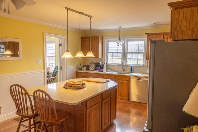 kitchen featuring light countertops, wainscoting, freestanding refrigerator, brown cabinets, and dishwasher