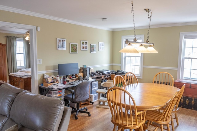 dining space with wood finished floors and crown molding