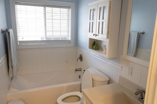 full bath with toilet, wainscoting, vanity, and a bath