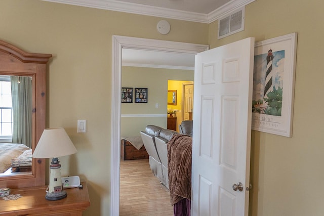 hall featuring ornamental molding, light wood-type flooring, and visible vents