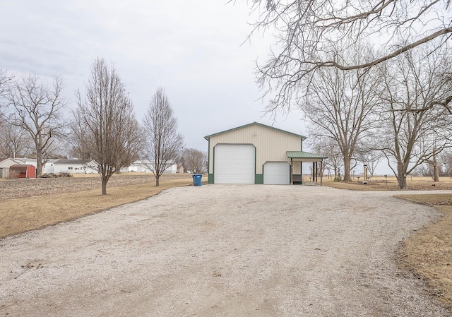 view of side of property with dirt driveway, a detached garage, and an outdoor structure