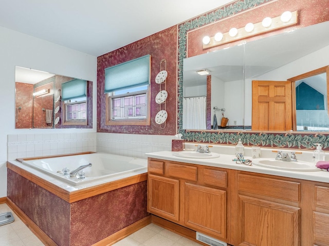 bathroom featuring a bath, visible vents, a sink, and tile patterned floors