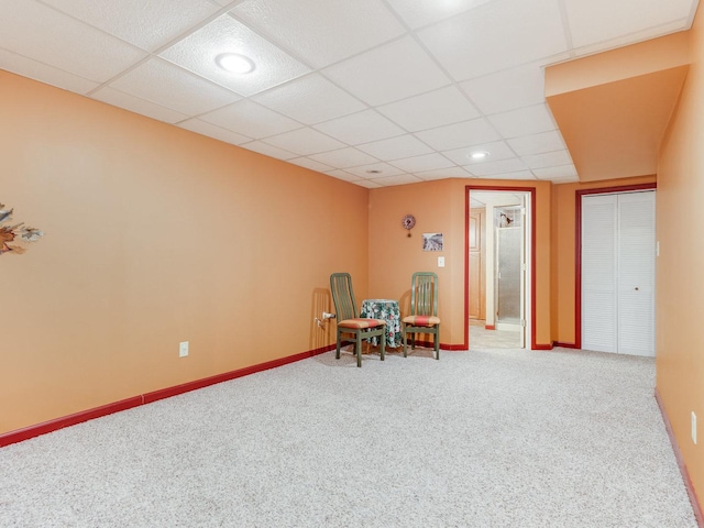 living area with baseboards, a drop ceiling, and carpet flooring