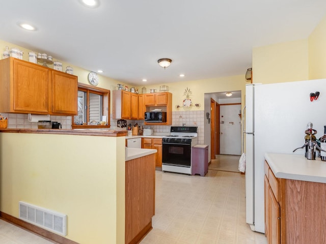 kitchen with light floors, tasteful backsplash, recessed lighting, visible vents, and white appliances