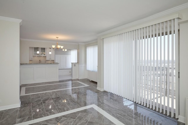 interior space featuring marble finish floor, a notable chandelier, crown molding, and a decorative wall