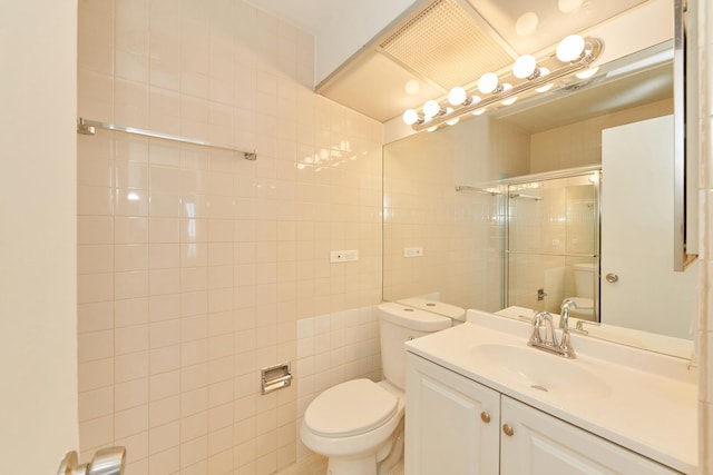 full bath with toilet, a tile shower, tile walls, and vanity