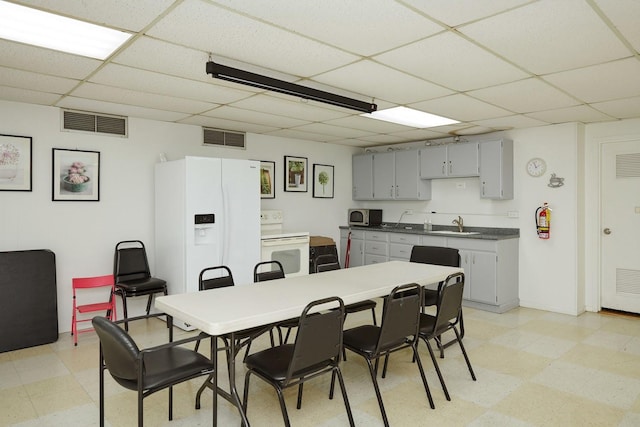 dining space with light floors, a drop ceiling, and visible vents