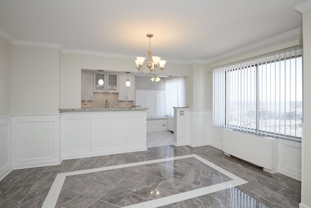 kitchen with marble finish floor, a decorative wall, wainscoting, and crown molding