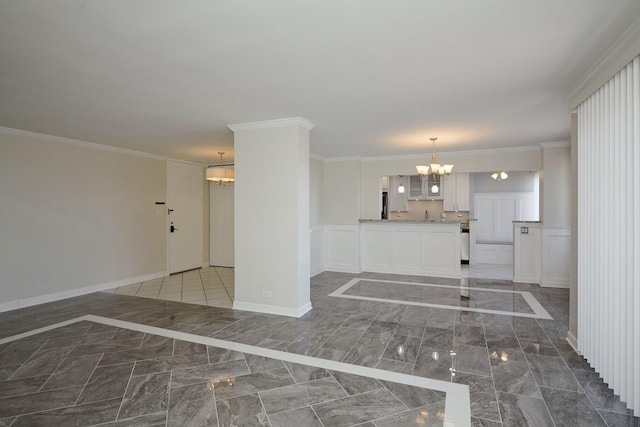 interior space featuring marble finish floor, a notable chandelier, a decorative wall, ornamental molding, and wainscoting