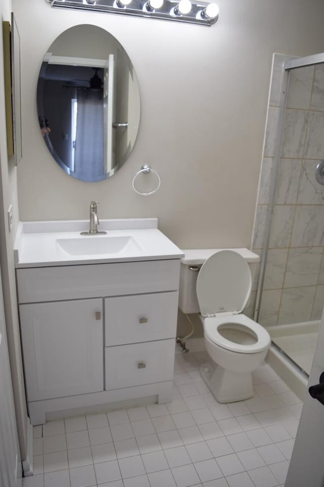 bathroom with a stall shower, vanity, toilet, and tile patterned floors