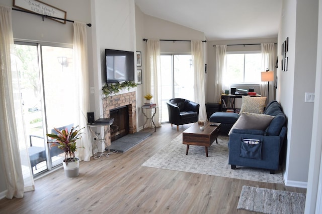 living room with high vaulted ceiling, a fireplace, and wood finished floors