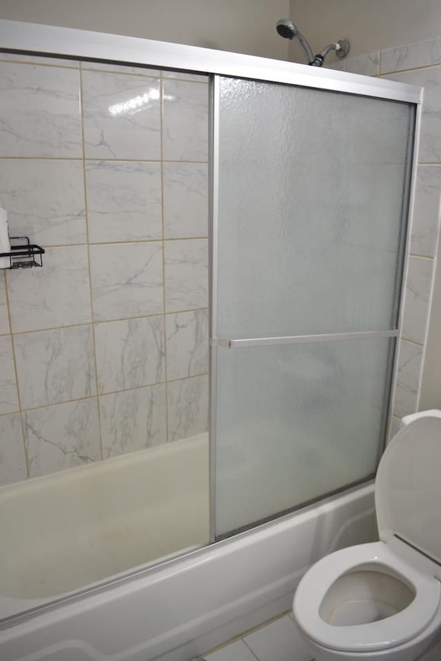 bathroom featuring toilet and combined bath / shower with glass door