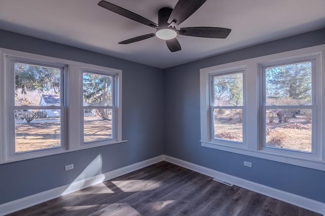 empty room featuring a ceiling fan, dark wood-style flooring, and baseboards