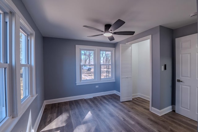 unfurnished bedroom with multiple windows, baseboards, and dark wood finished floors