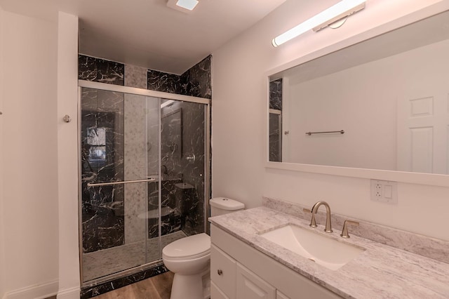 bathroom featuring vanity, wood finished floors, a shower stall, and toilet