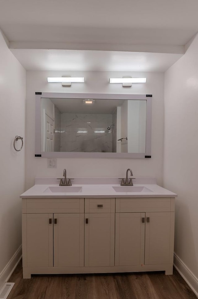 full bathroom featuring a tile shower, double vanity, a sink, and visible vents