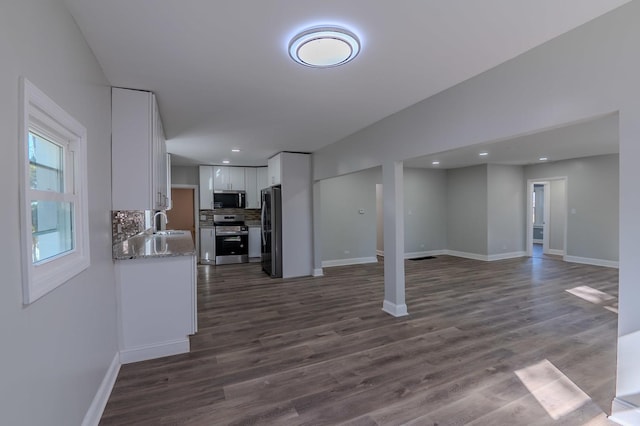 kitchen featuring a sink, white cabinets, open floor plan, appliances with stainless steel finishes, and backsplash