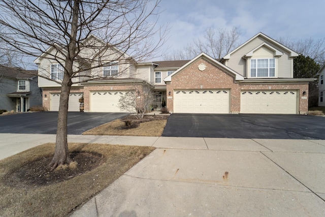 traditional-style home featuring a garage, driveway, and brick siding