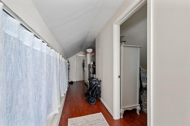 hallway featuring baseboards, vaulted ceiling, and wood finished floors