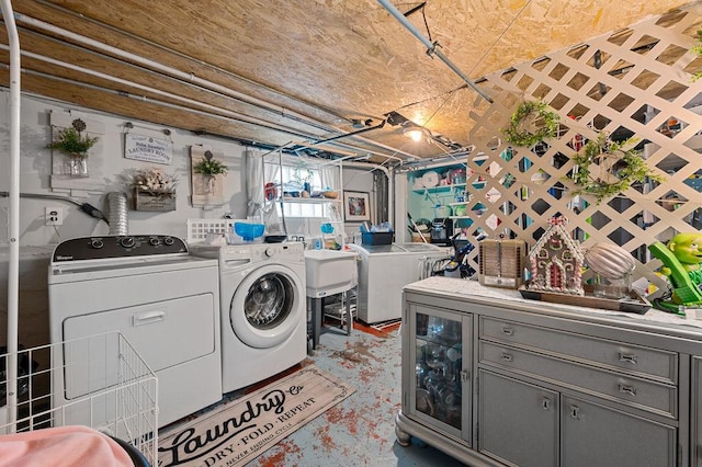 washroom with laundry area, a sink, and washing machine and clothes dryer