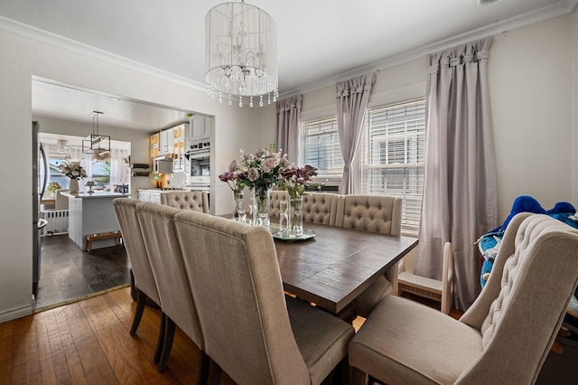 dining area with an inviting chandelier, ornamental molding, and hardwood / wood-style floors